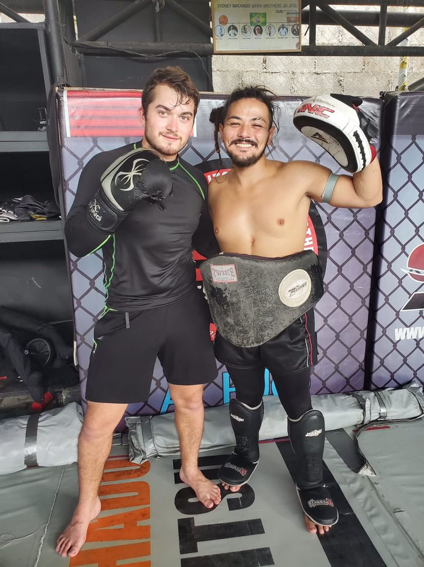 Matt holding pads while coaching a student in a Thailand gym