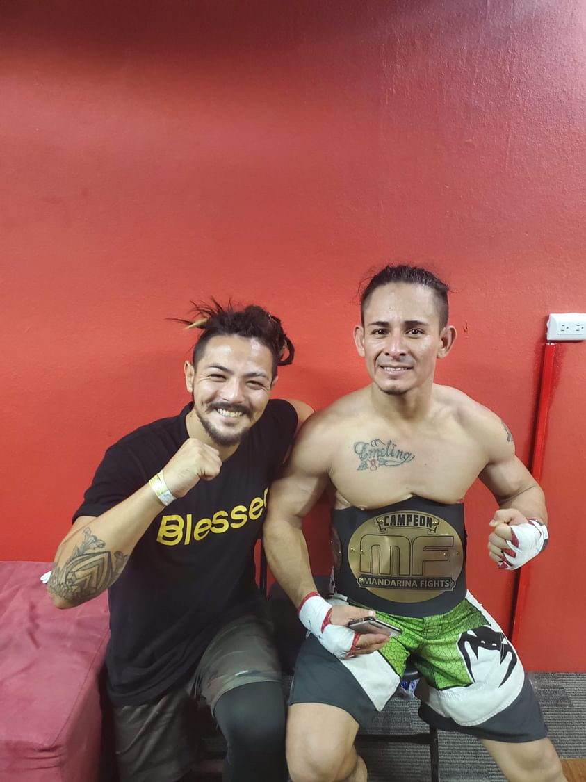 Matt with a fighter wearing a championship belt after his win
